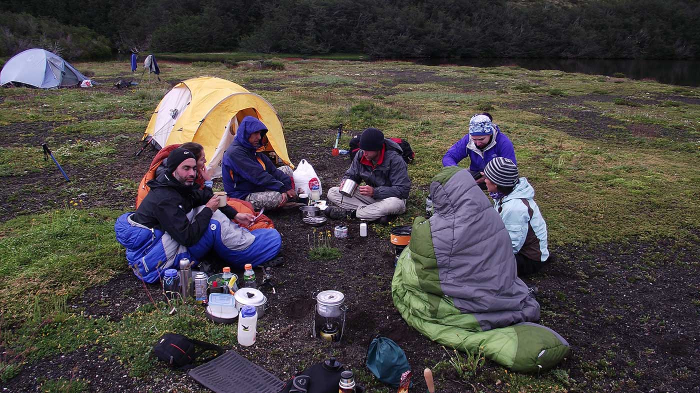 Personas sentadas en sacos de dormir hacienda camping,