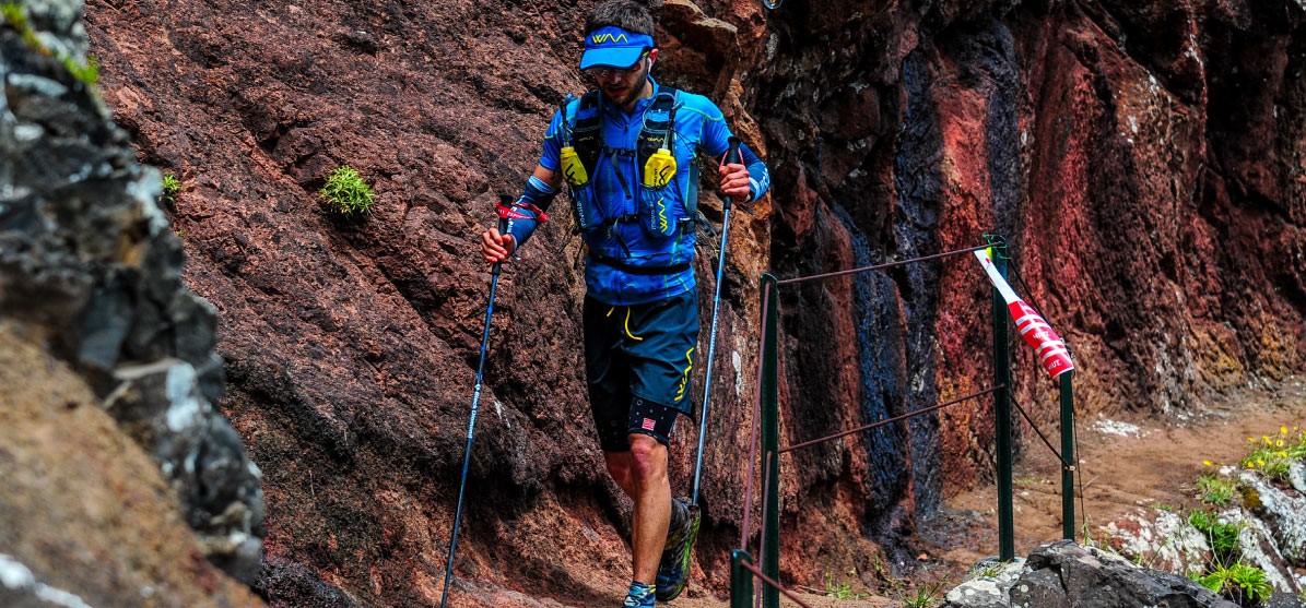 Hombre con bastones y sistema de hidratación realizando Trail Running.